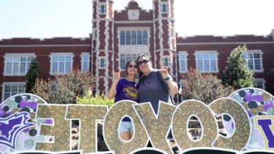 Student by Coyote move-in sign with parent